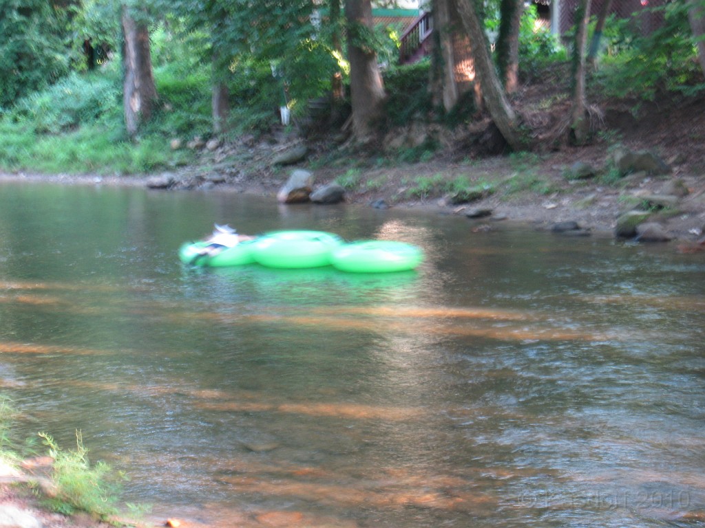 Helen to Unicoi 2010 0520.jpg - I had just gotten back to the hotel, walked out to the river to cool down when this guy with the toughest summer job came along. It took a minute to dig out my camera from the zip lock bag... This guy floates down the river at the end of the day and lasso's abandoned tube floats. He hooks them together with straps and floated down river until he spots the next empty tube.